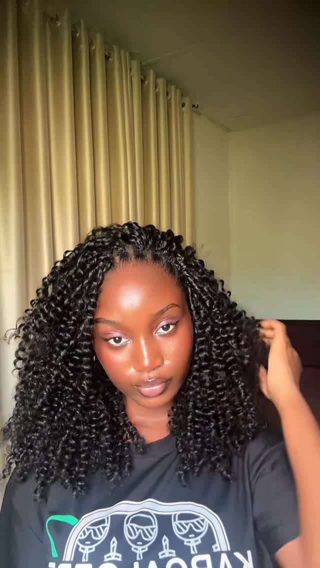 12 Braids Hairstyles: 16 Ideas From Box Braids to Cornrows 13 Woman with long, voluminous black curly crochet braids posing indoors against beige curtains.
