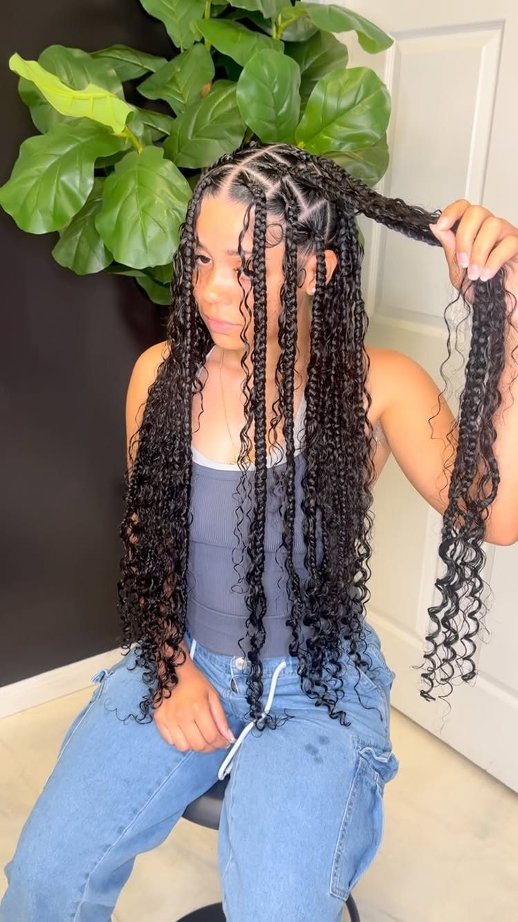 12 Braids Hairstyles: 16 Ideas From Box Braids to Cornrows 10 Woman with long black knotless braids and curly ends wearing blue clothing.