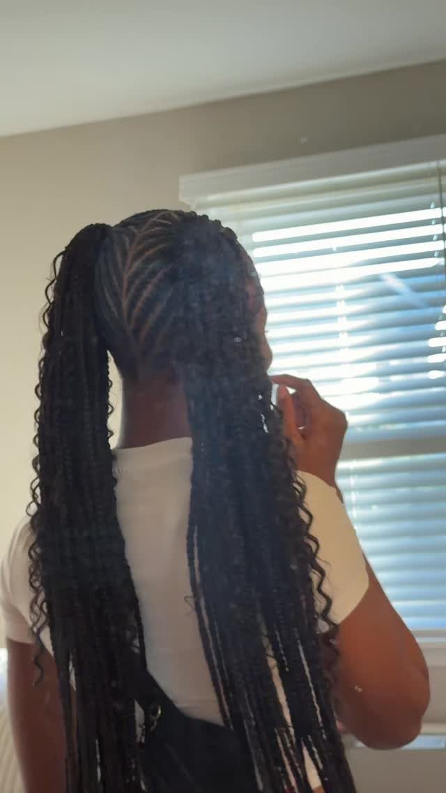 Two long black braided pigtails with curly ends on a person's head.