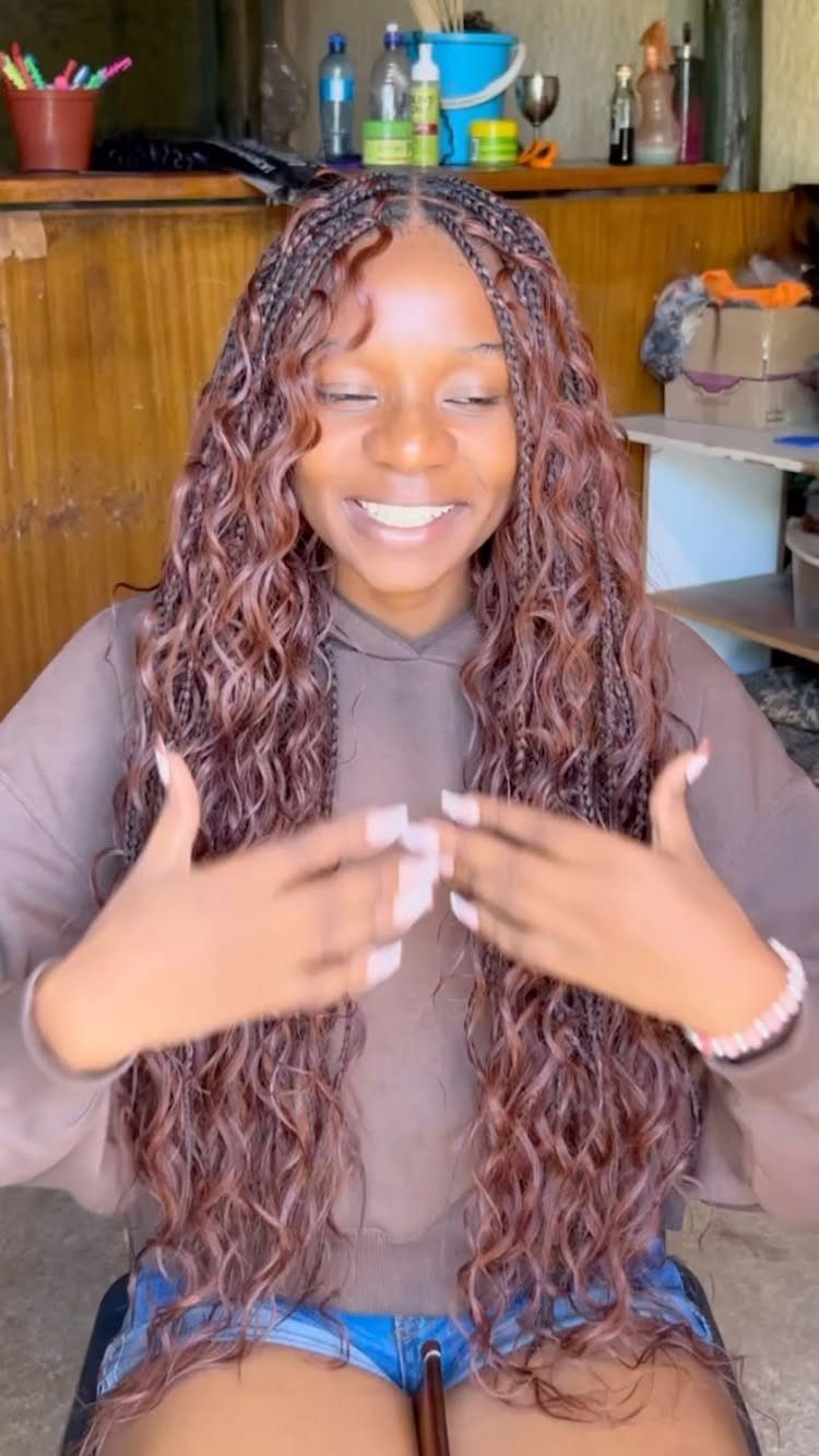 33 Hair Color vs. Color 5: 5 Ideas for Braids and Curls 1 Woman with long reddish-brown box braids and curly ends smiling in a room.