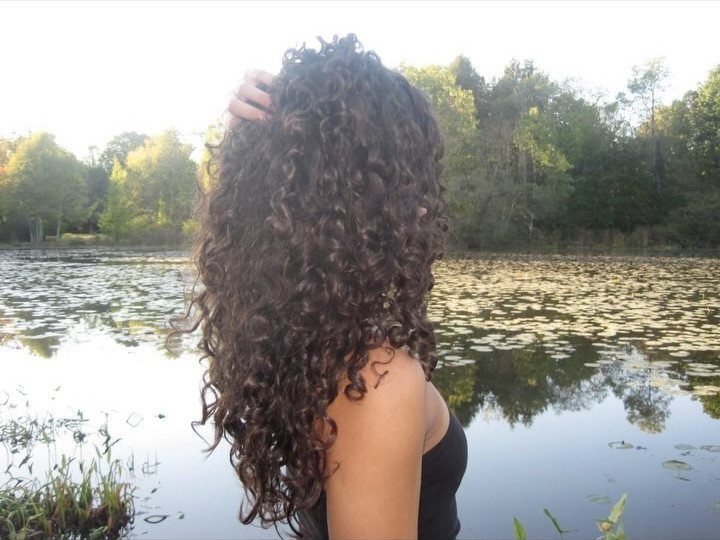 3A Hair Long: 4 Ideas for Pineapples, Ringlets and More 3 Woman with long, dark brown spiral curls standing before a calm pond.