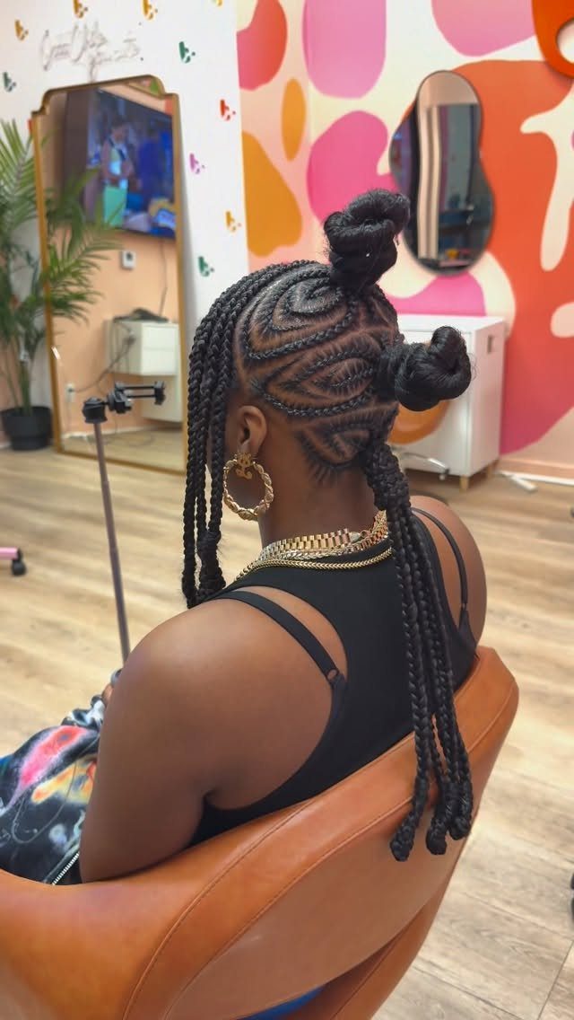 16 Big Cornrow Hairstyles for Bold, Standout Looks 6 Woman with black cornrow braids styled into two Bantu knots and long braids.