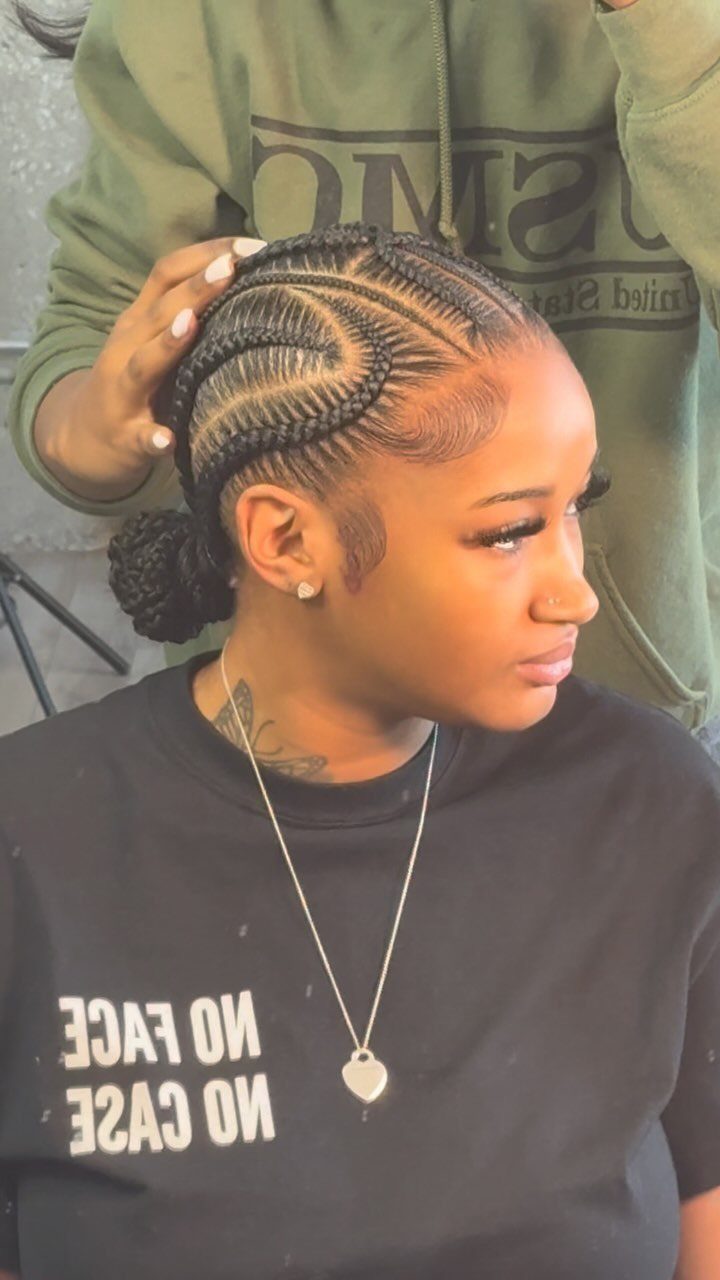 16 Big Cornrow Hairstyles for Bold, Standout Looks 14 Woman with crisscrossed cornrow braids styled into a bun and a heart necklace.