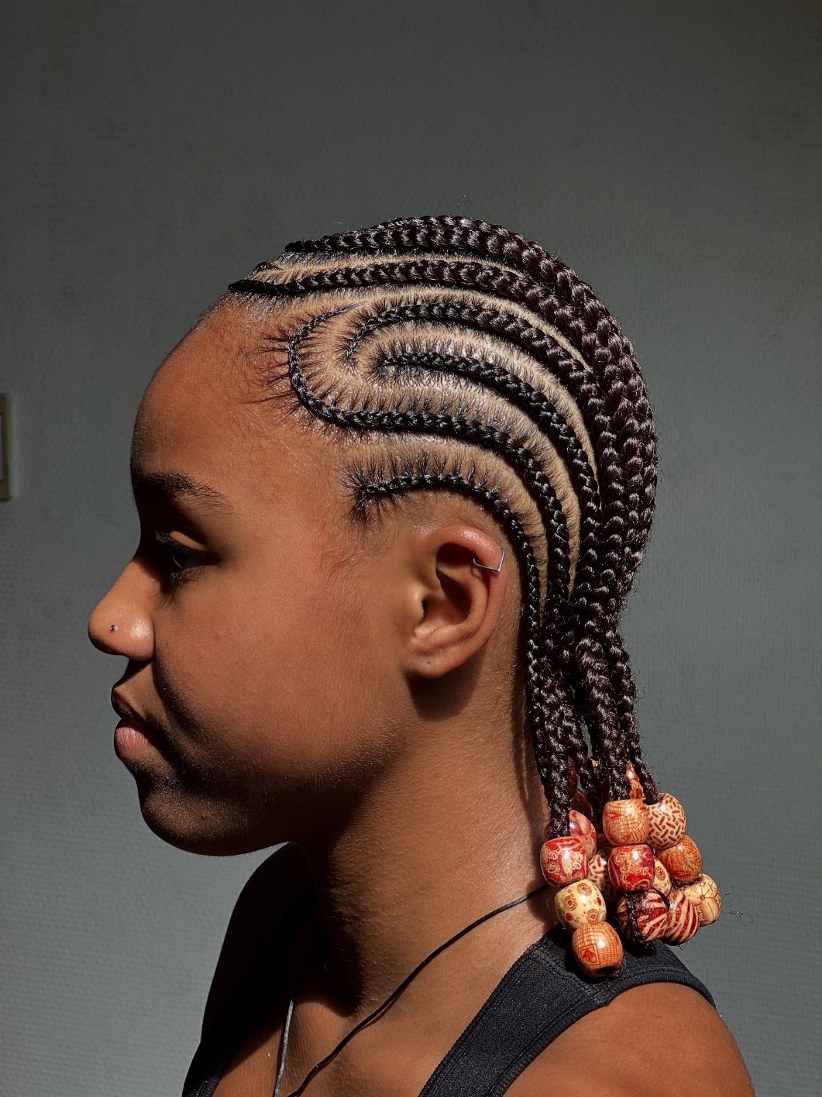 31 Black Hair Natural Hairstyles for Every Length 12 Person with intricate curved cornrow braids decorated with wooden beads at the ends.