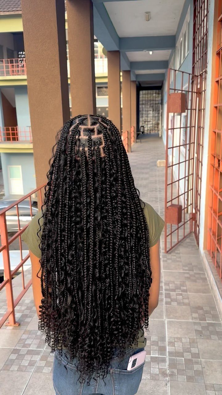 31 Black Hair Natural Hairstyles for Every Length 30 Long black curly micro-braids on a person standing in an outdoor corridor