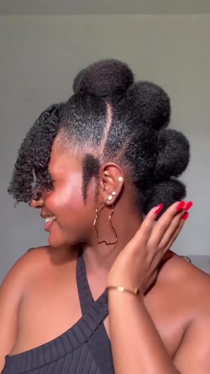 31 Black Hair Natural Hairstyles for Every Length 24 Woman with black hair styled in a series of curly puffs and fringe.