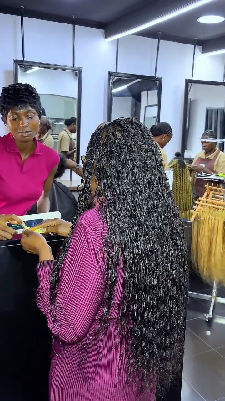 15 Braid Hairstyles for Thick Hair, From Bubble to Boho 7 Woman with long curly black goddess braids standing in a hair salon