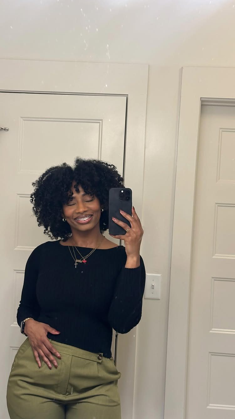 How to Style a Braid Out Afro: 5 Ideas for Every Length 2 Woman with a voluminous curly afro hairstyle taking a mirror selfie indoors.