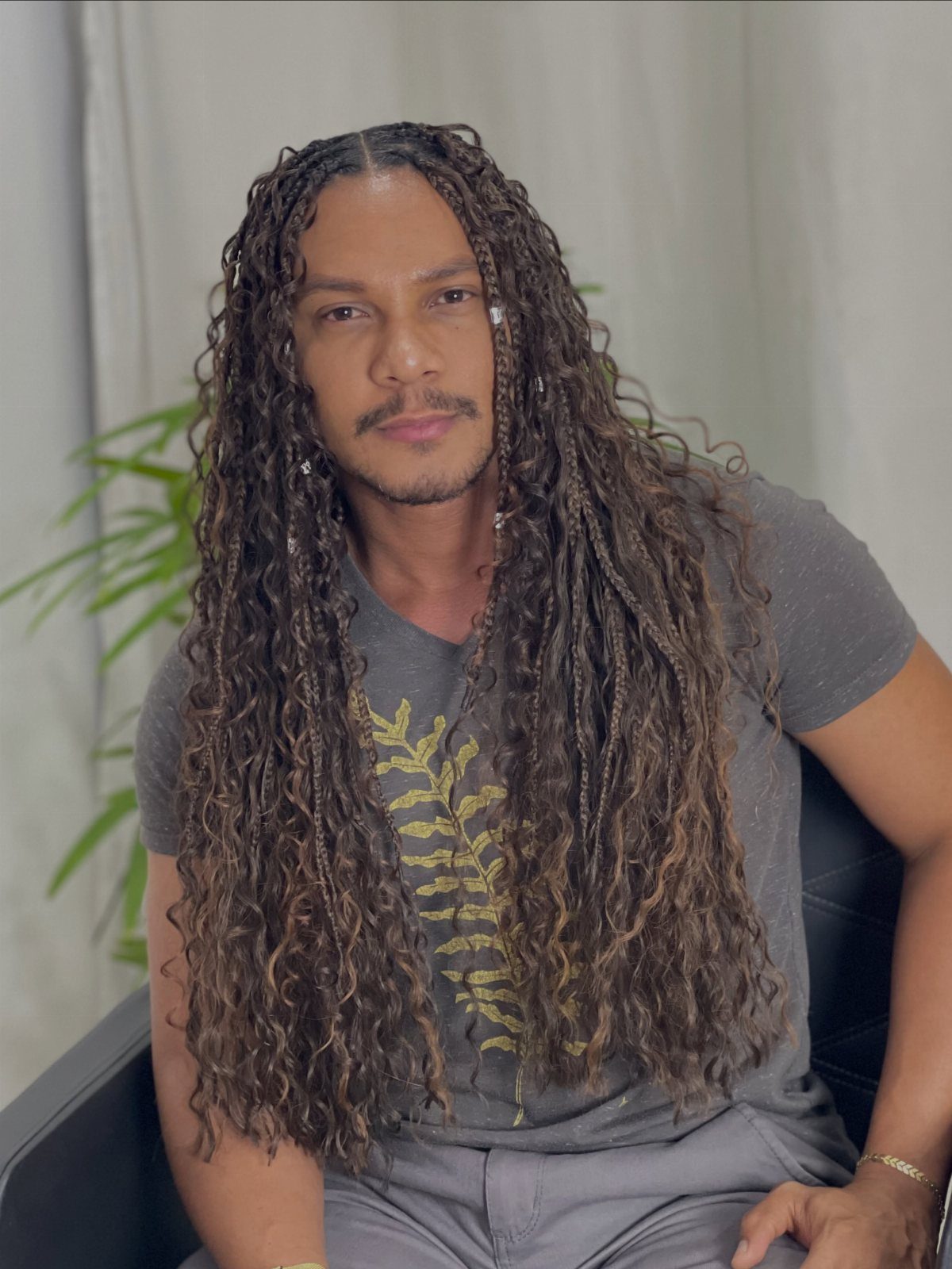 11 Braided Mens Hairstyles: Cornrows, Box Braids and More 1 Man with long brown braided hair and curly ends wearing a grey t-shirt.