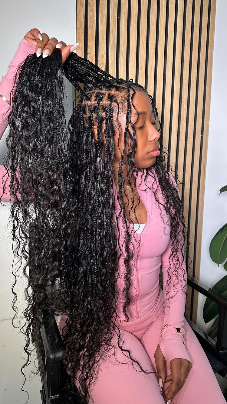 16 Braids Going Back with Curls: Styles to Try 4 Woman with long black goddess braids and curly ends wearing a pink outfit.
