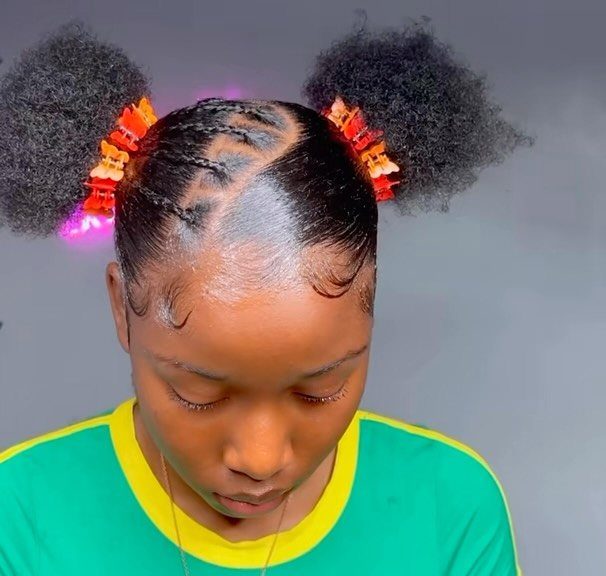9 Braids with Natural Hair Only: Styles Without Extensions 3 Woman with cornrows styled into two curly puff buns with orange clips.
