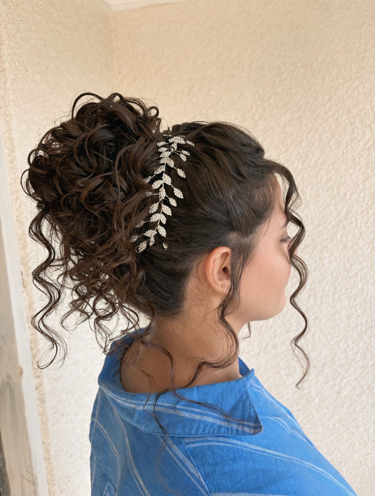 8 Ideas for a Bun with Curls, From High to Low 8 Woman with a high curly bun hairstyle and silver leaf hair accessory