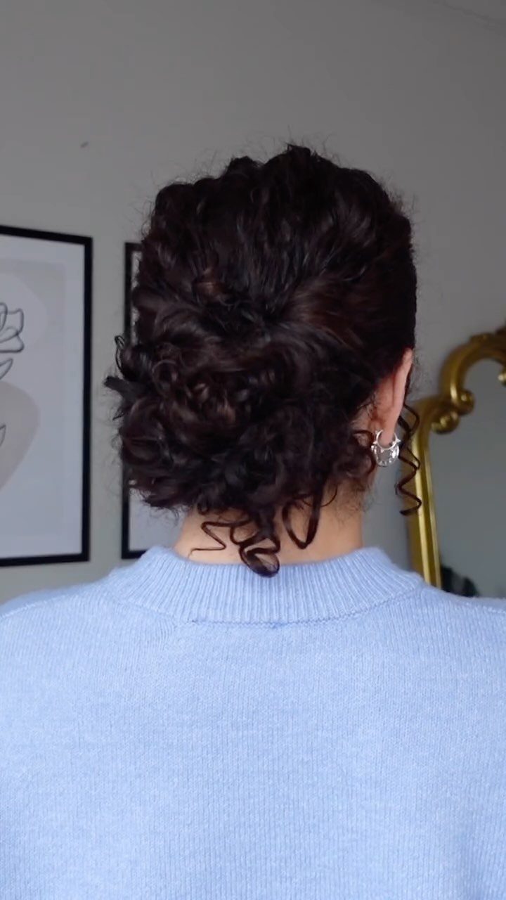 8 Ideas for a Bun with Curls, From High to Low 3 Dark brown curly hair styled into a low bun at the neck.