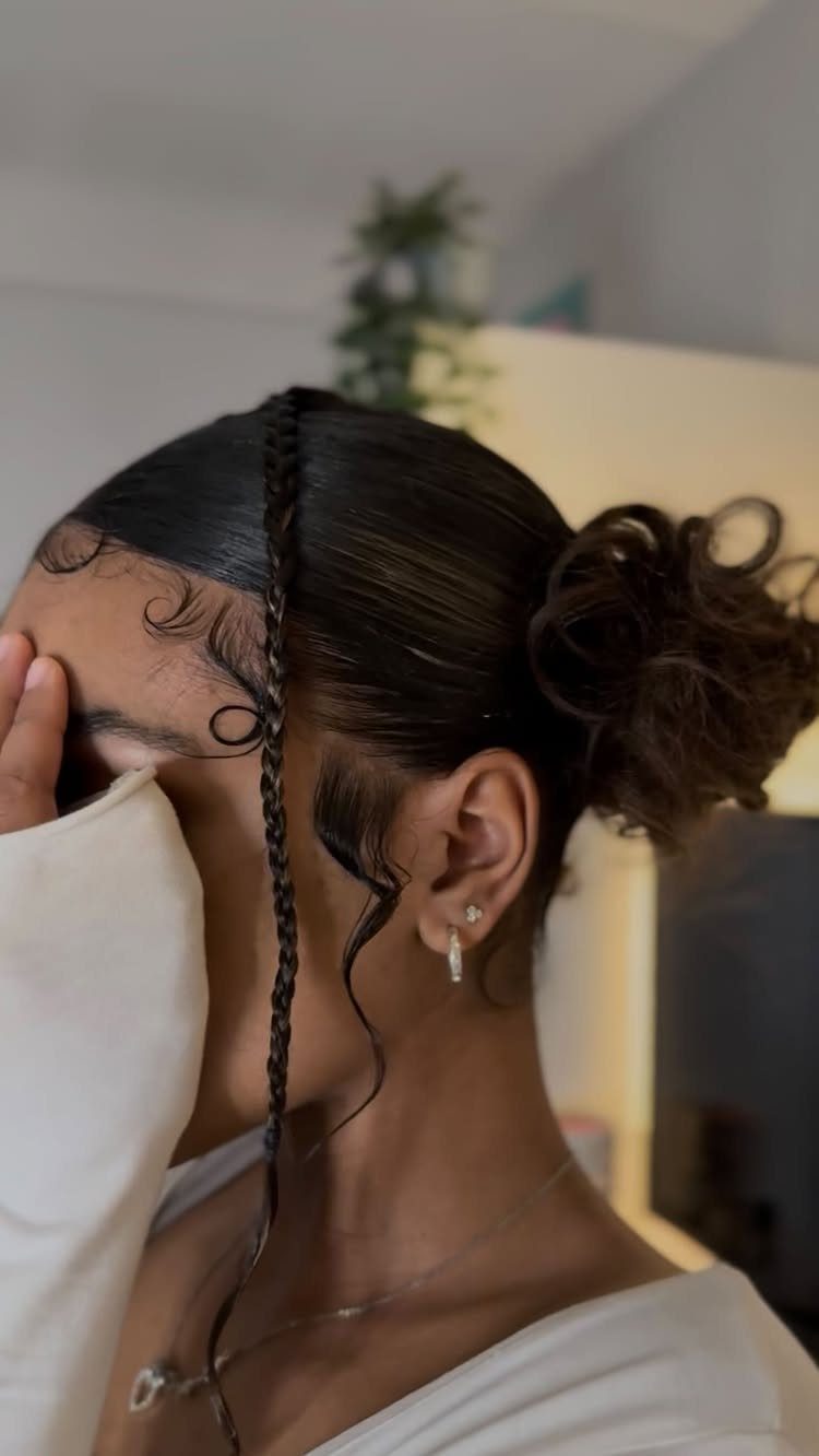 Buns for Curly Hair: 7 Ideas, From Messy to Floral 5 Person with dark curly hair styled in a low bun and center braid.