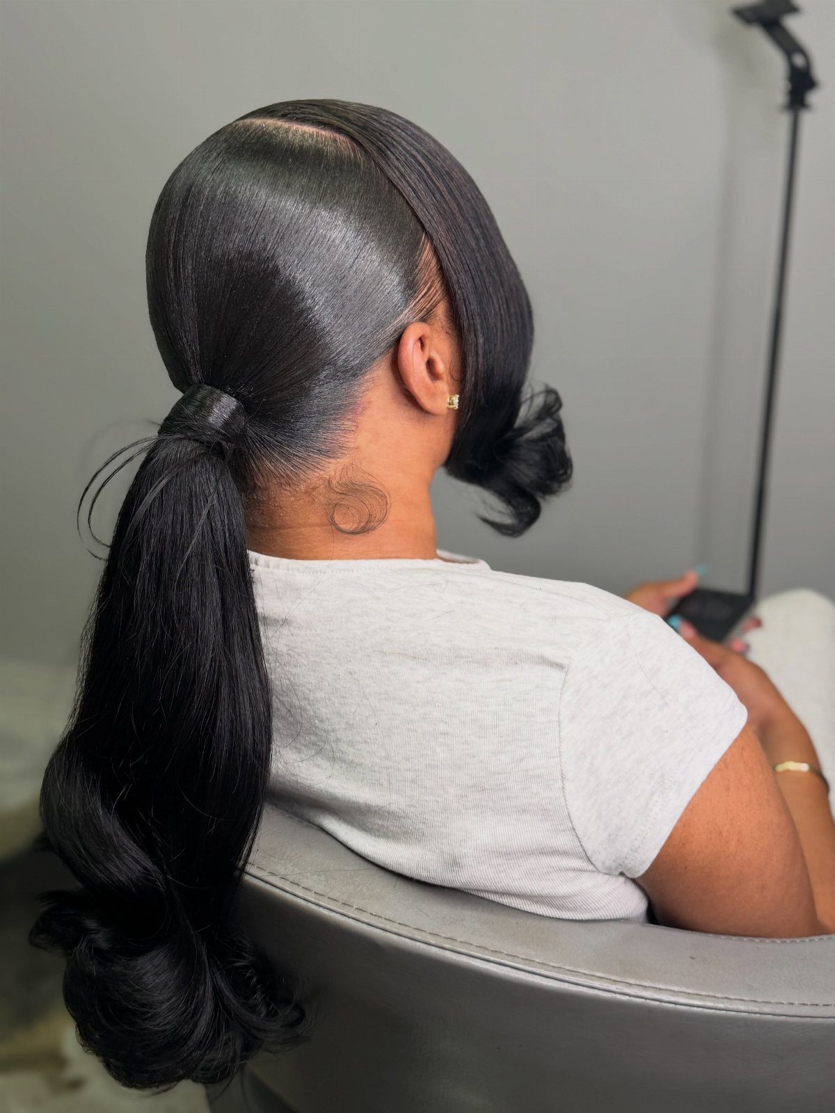 9 Business Casual Hairstyles for Women at the Office 2 Woman with a sleek low ponytail and polished black hair in a salon.