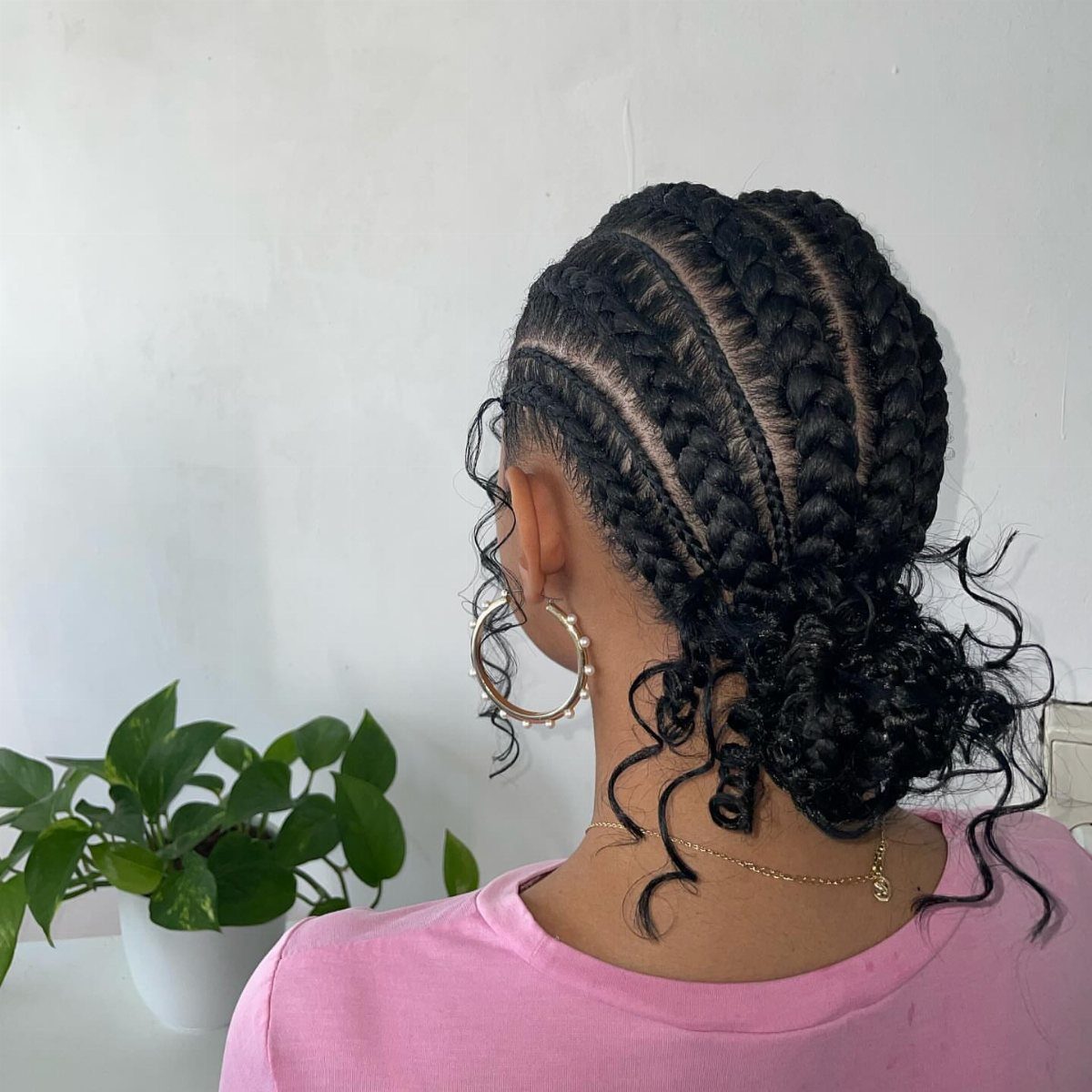 Cornrows Braids with Curls: 13 Ideas for Every Style 13 Black cornrow braids ending in a curly bun on a person in pink.