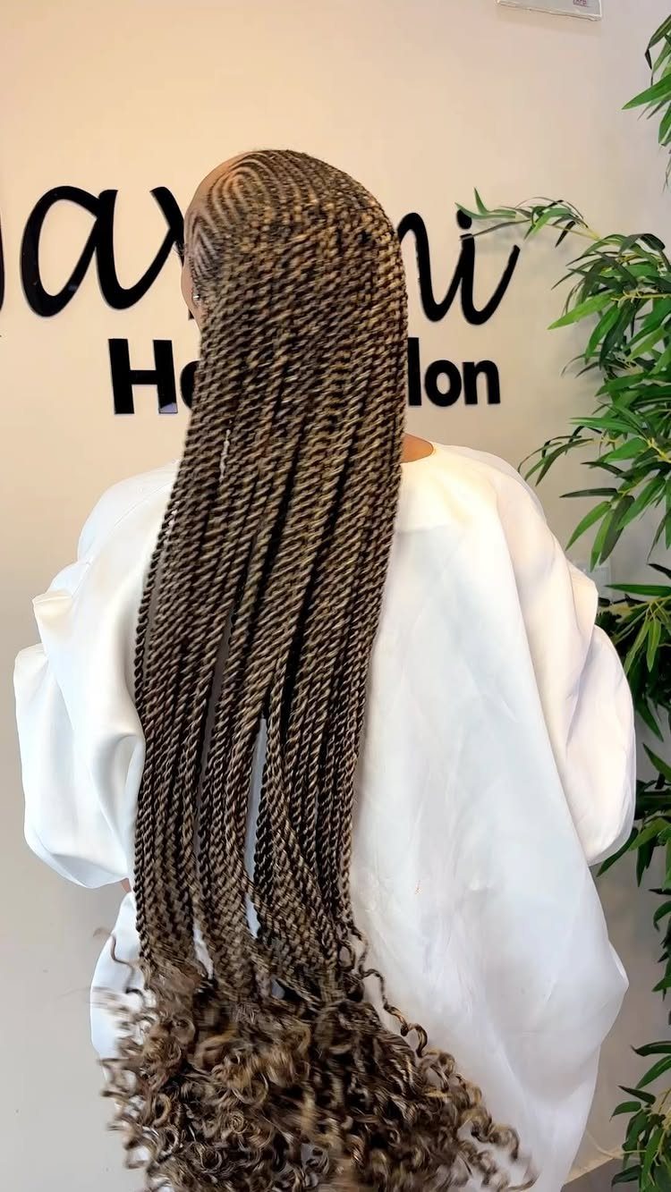 Long brown twisted braids starting from cornrows on a person in a salon.