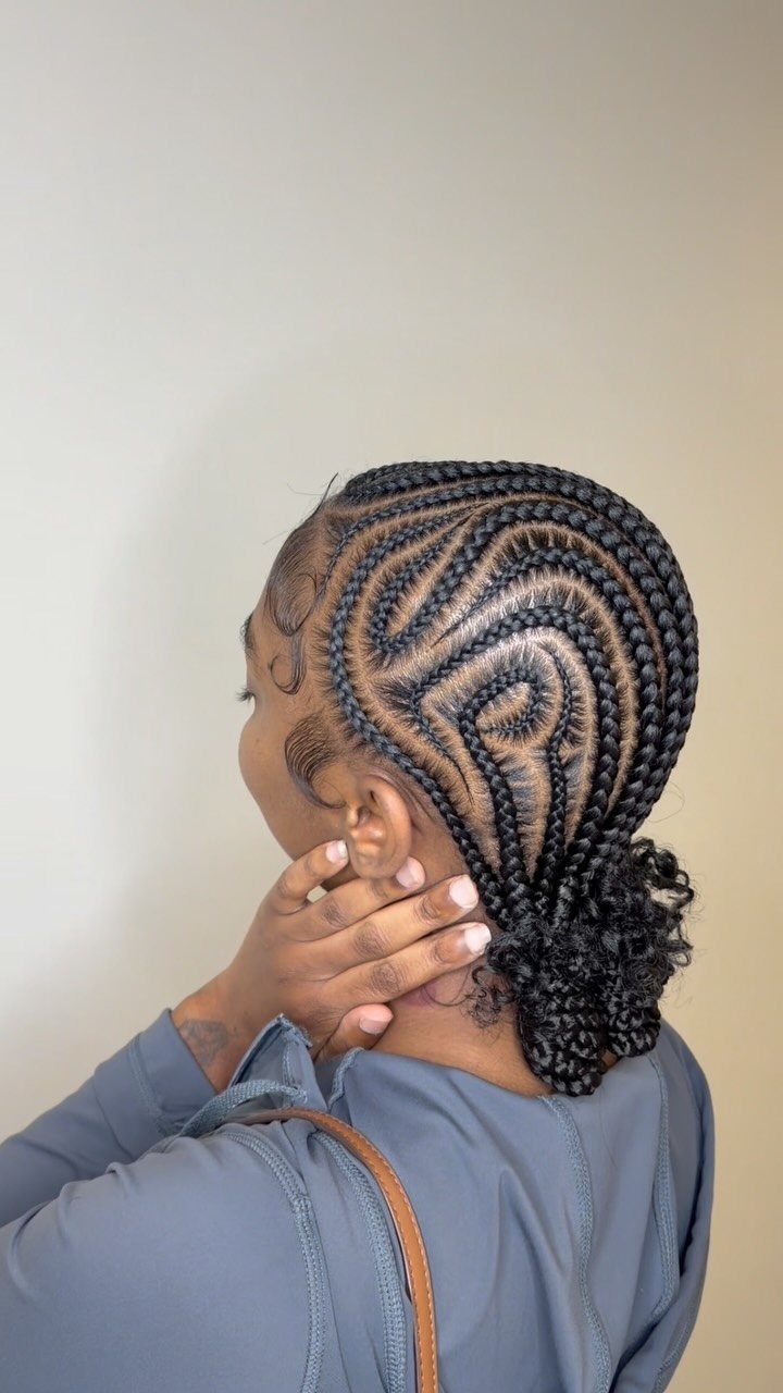 Woman with curved cornrows transitioning into box braids tied in a low bun.