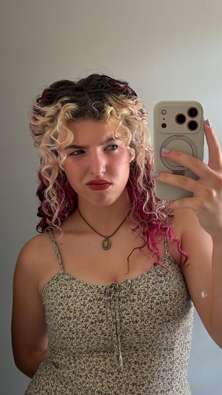Curly Hair Beauty Ideas: 11 Styles, Colors and Care 8 Woman with multi-colored curly hair taking a mirror selfie in a floral dress.