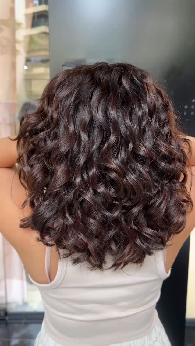 Curly Hair Design: 10 Ideas for Every Length and Texture 6 Shoulder-length voluminous dark brown curly hair seen from the back.