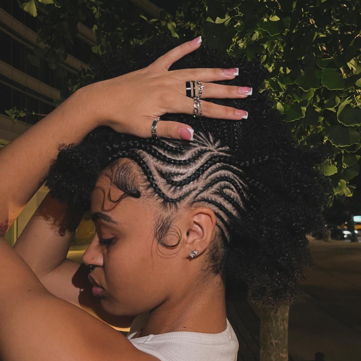 Curly Hair Design: 10 Ideas for Every Length and Texture 9 Woman with a frohawk hairstyle featuring side cornrow braids and voluminous curly hair.