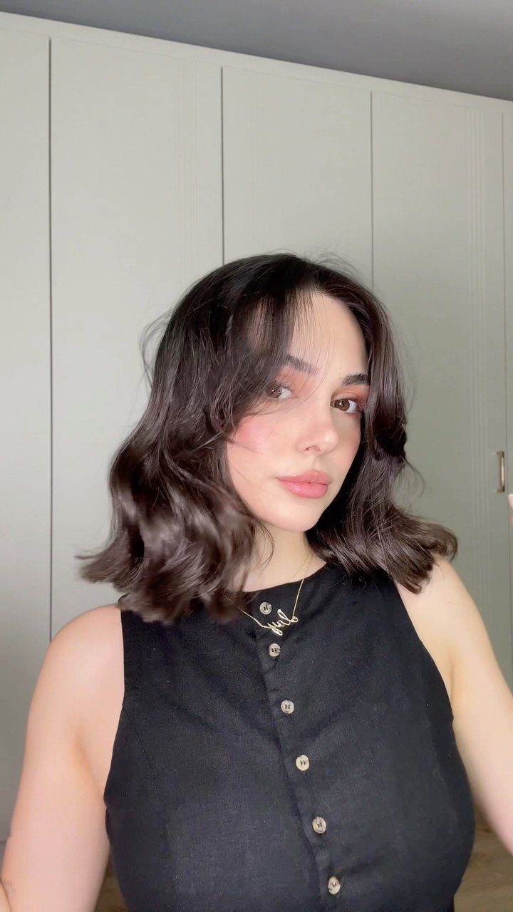 11 Cute Easy Work Hairstyles for Busy Mornings 6 Woman with shoulder-length dark brown hair styled in voluminous, bouncy waves.