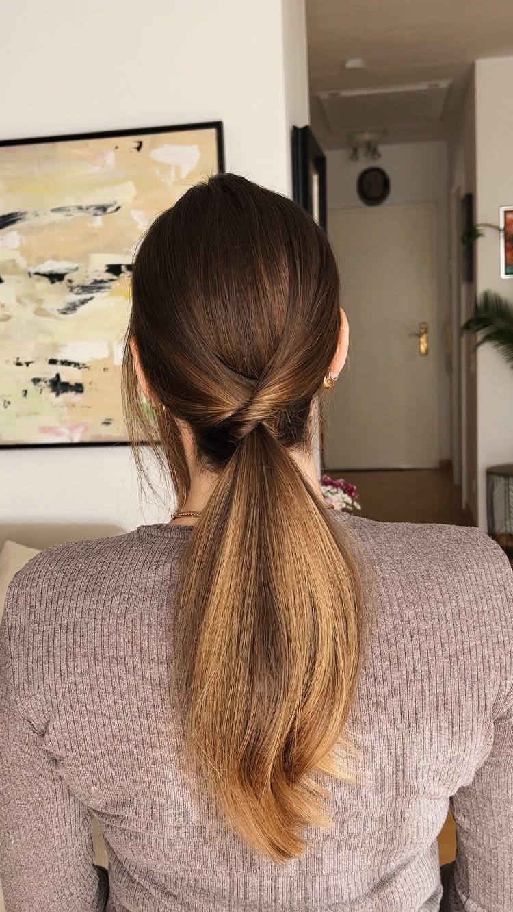 11 Cute Easy Work Hairstyles for Busy Mornings 8 Woman with brown hair in a twisted ponytail wearing a beige ribbed sweater.