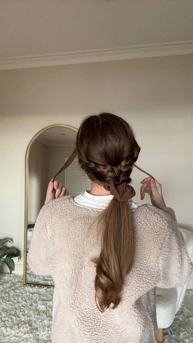 9 Cute Hair Styles for Church, From Buns to Box Braids 2 Woman with a braided low ponytail and brown scrunchie wearing a beige sweater.