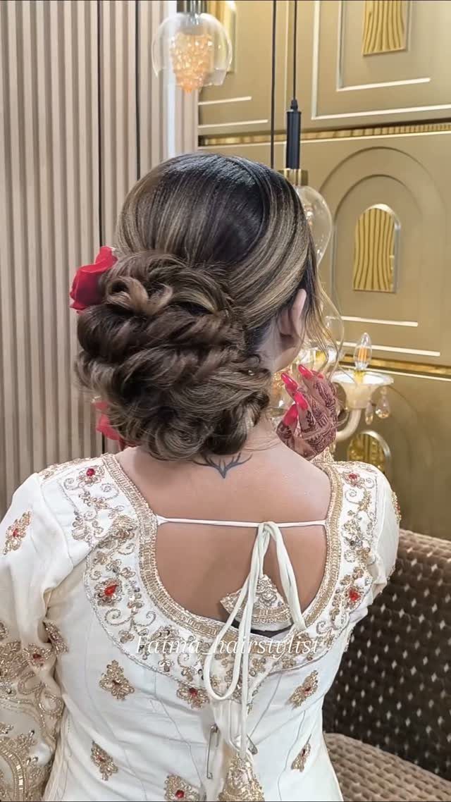 9 Cute Hair Styles for Church, From Buns to Box Braids 1 Low twisted hair bun with a red flower on a person wearing white embroidery.