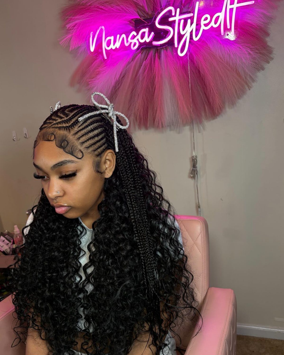 16 Cute Hairstyles for a Birthday Party, Waves to Braids 14 Woman with curly black hair and side cornrow braids with a silver bow.
