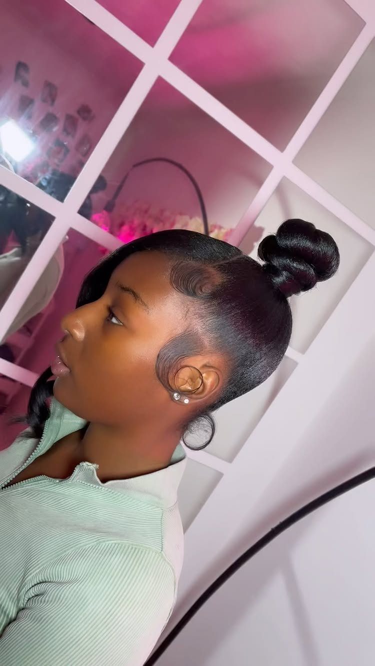 16 Cute Hairstyles for a Birthday Party, Waves to Braids 11 Woman with dark hair styled in a sleek high top knot bun.
