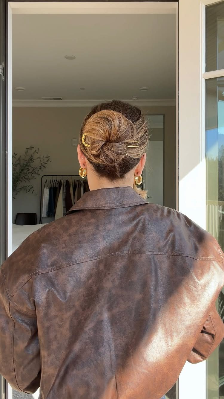 16 Cute Hairstyles for a Birthday Party, Waves to Braids 2 Woman with a sleek twisted low bun secured by gold hairpins wearing leather jacket