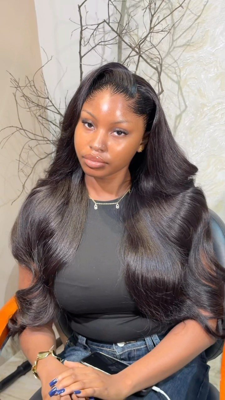 16 Cute Hairstyles for a Birthday Party, Waves to Braids 4 Woman with long, dark, voluminous bouncy curls wearing a black top and jeans.