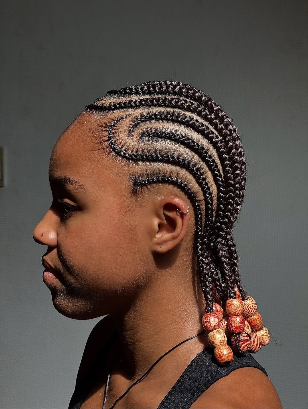 17 Cute Hairstyles for Picture Day, From Braids to Buns 10 Person with curved cornrow braids decorated with colorful beads at the ends.
