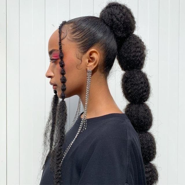 17 Cute Hairstyles for Picture Day, From Braids to Buns 14 Woman with a high vertical stack of hair puffs and face-framing braids.