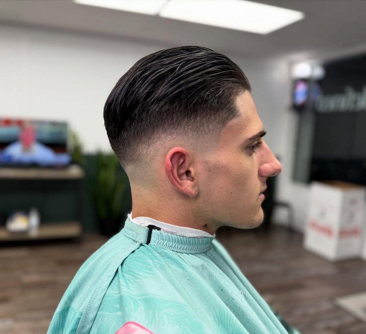 11 Cute Slick Backs: Braids, Buns, Ponytails and a Fade 8 Man with dark hair styled in a glossy slick-back and high skin fade.