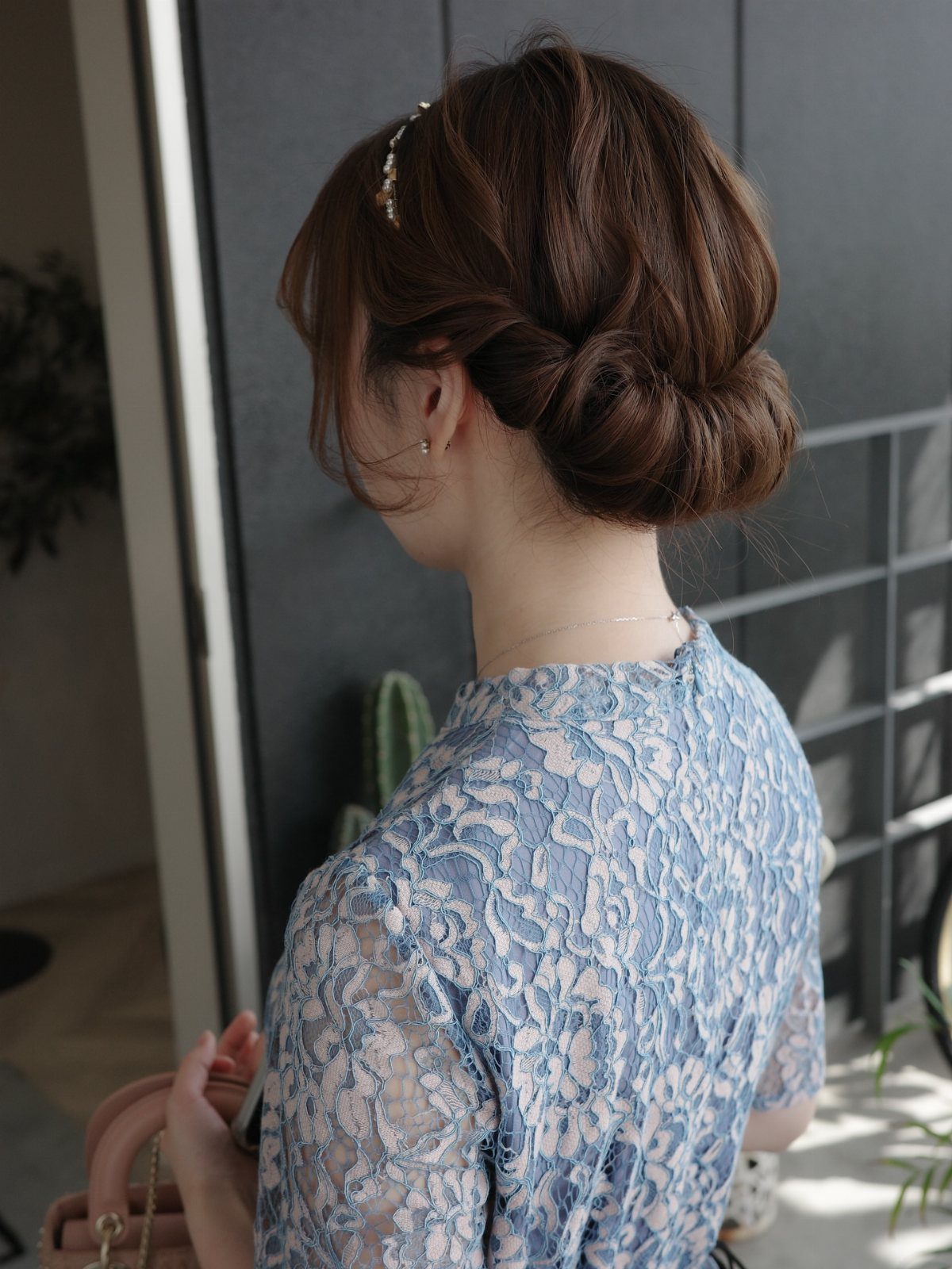 Woman with brown hair styled in a low Gibson tuck rolled bun.