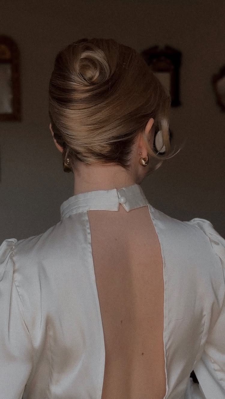 Blonde woman from behind with a polished low chignon updo and white dress