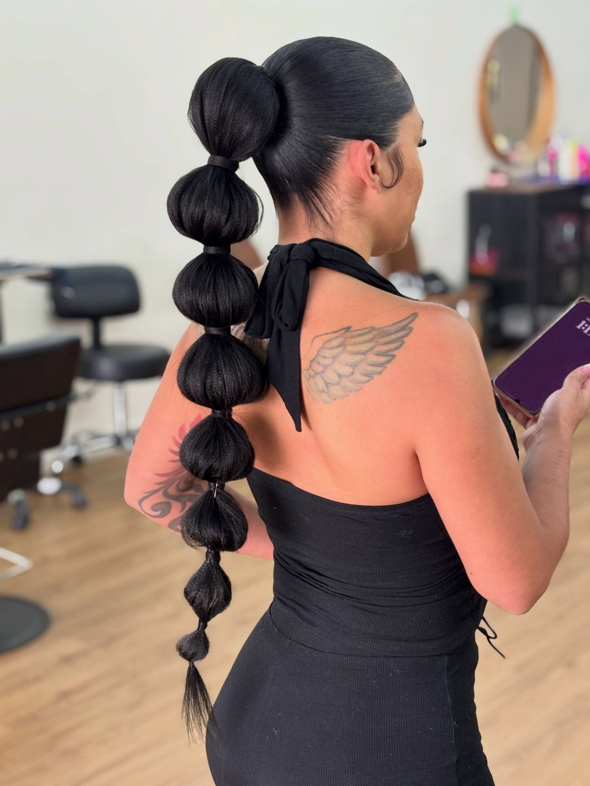 12 Cute Updo Hairstyles for Easy Everyday Styling 6 Woman with a high bubble ponytail hairstyle and a wing tattoo on her shoulder.