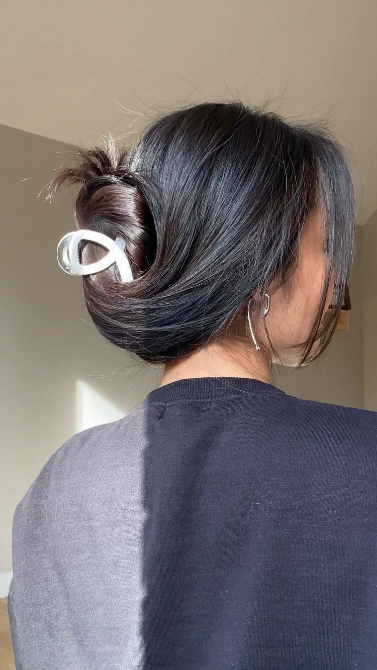 12 Cute Updo Hairstyles for Easy Everyday Styling 2 Dark hair styled in a twisted updo secured with a white claw clip.