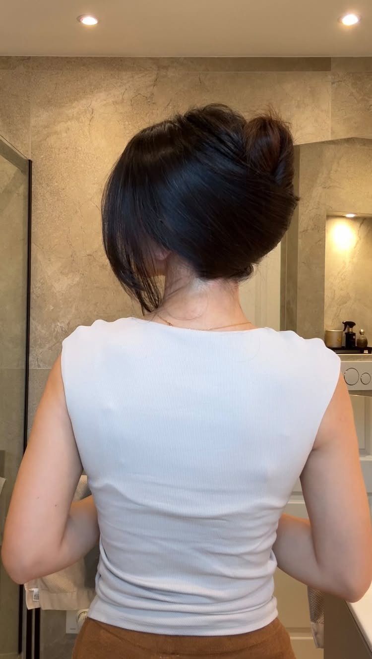 12 Cute Updo Hairstyles for Easy Everyday Styling 10 Woman with dark hair styled in a loose low updo bun from behind