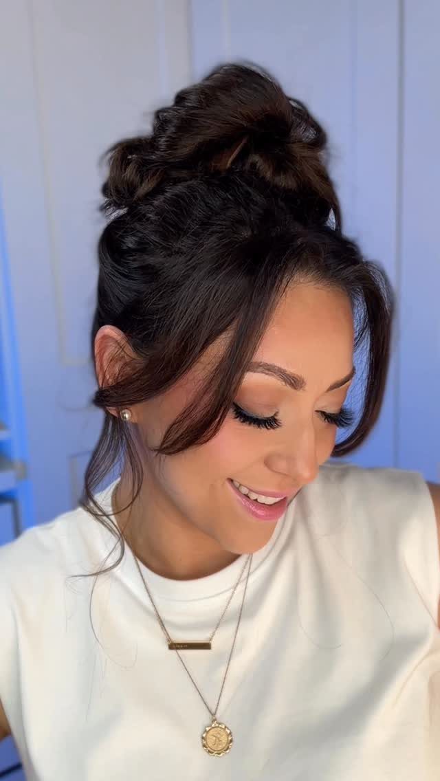12 Cute Updo Hairstyles for Easy Everyday Styling 3 Woman with brown hair styled in a high messy bun and loose tendrils.