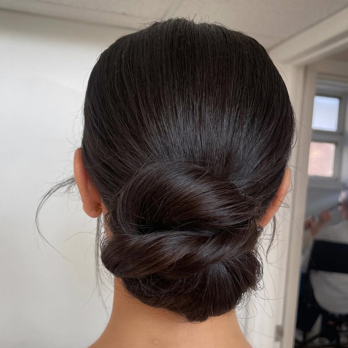 12 Cute Updo Hairstyles for Easy Everyday Styling 7 Dark brown hair styled into a sleek, low twisted bun at the nape.