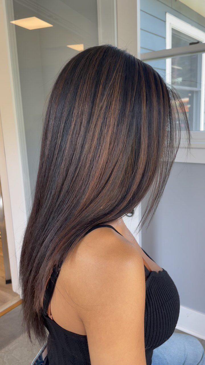 16 Dark Brunette Hair Color Ideas for Every Skin Tone 3 Woman with long dark brown hair and warm caramel brown highlights.