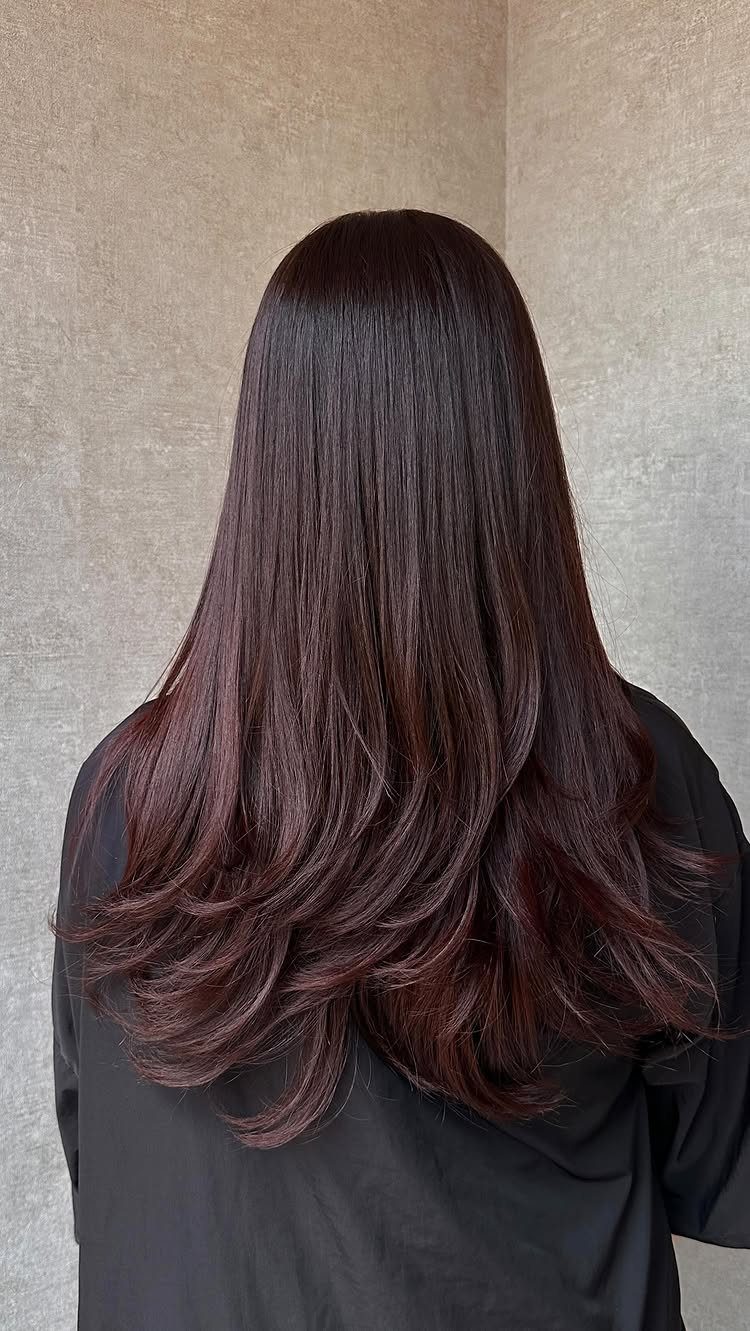 16 Dark Brunette Hair Color Ideas for Every Skin Tone 9 Long wavy hair in a dark chocolate cherry reddish-brown shade from behind.
