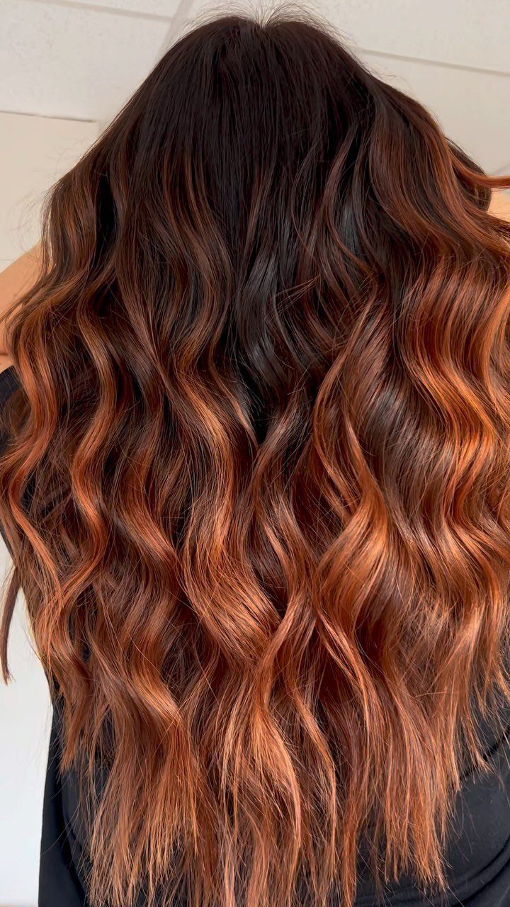 16 Dark Brunette Hair Color Ideas for Every Skin Tone 1 Long wavy dark brown hair with vibrant copper balayage highlights from back view