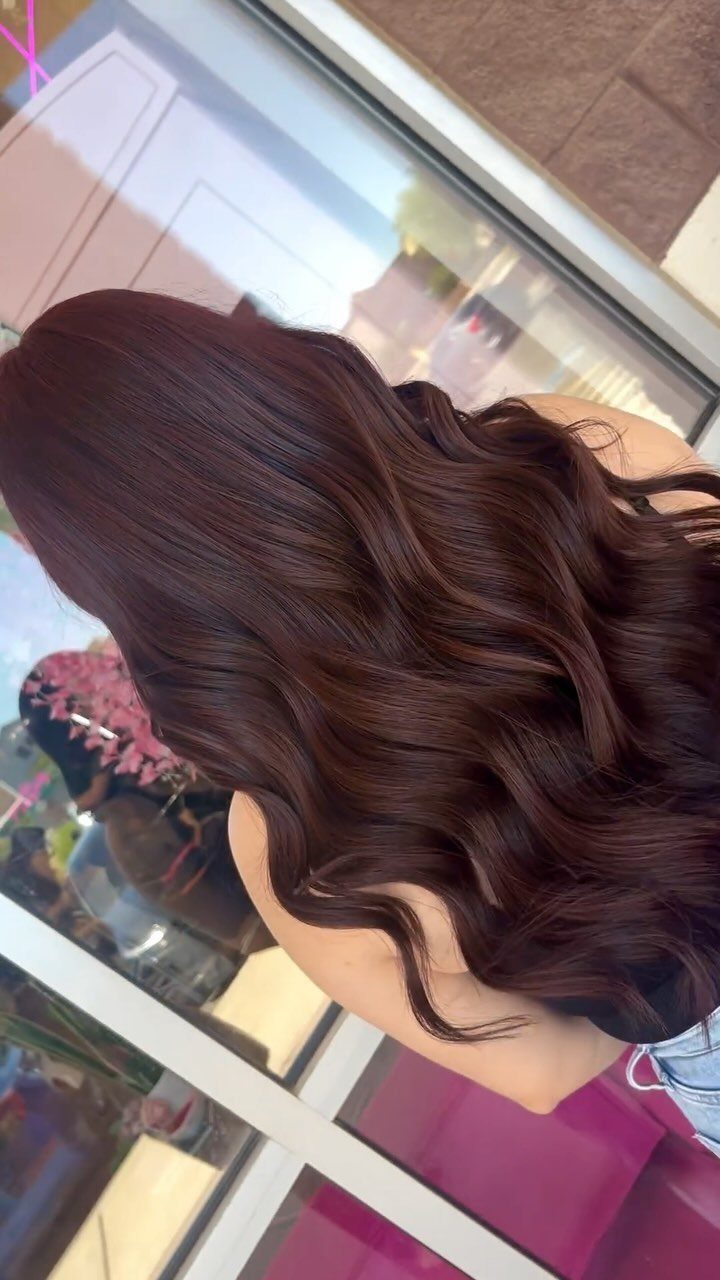 16 Dark Brunette Hair Color Ideas for Every Skin Tone 7 Long wavy mahogany brown hair viewed from behind in a bright indoor setting