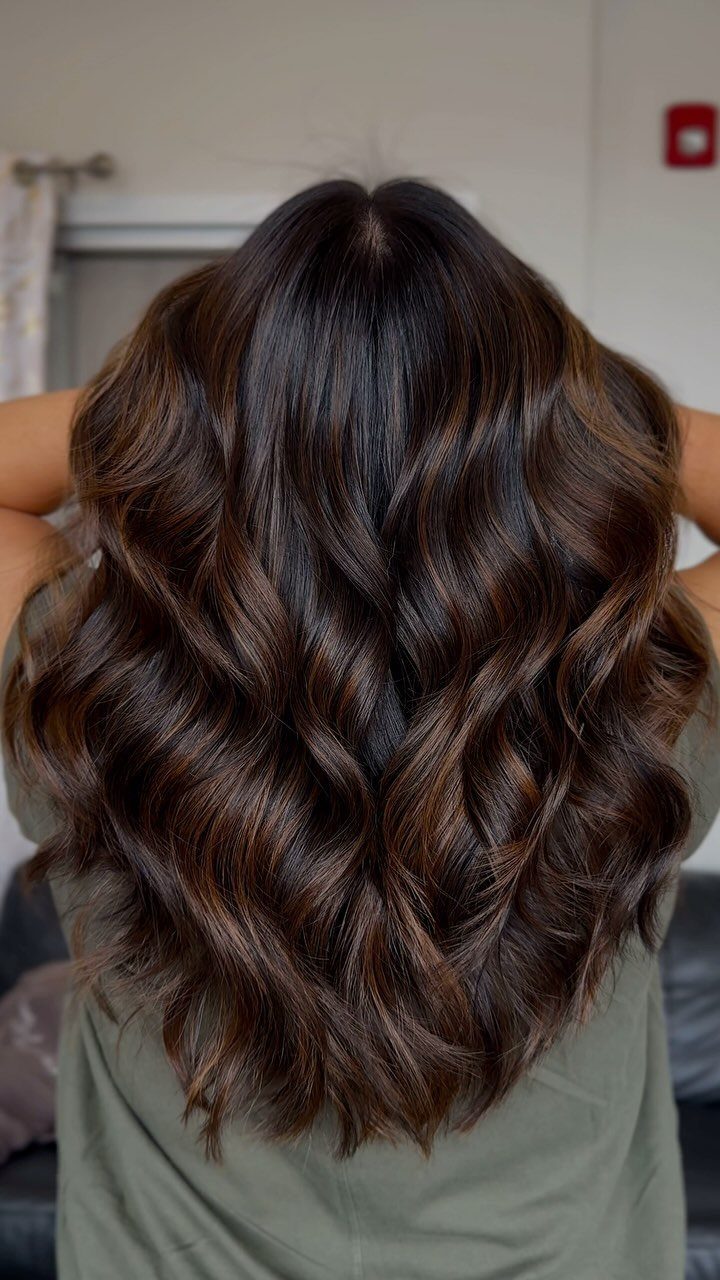 16 Dark Brunette Hair Color Ideas for Every Skin Tone 6 Long wavy dark brown hair with warm highlights seen from the back