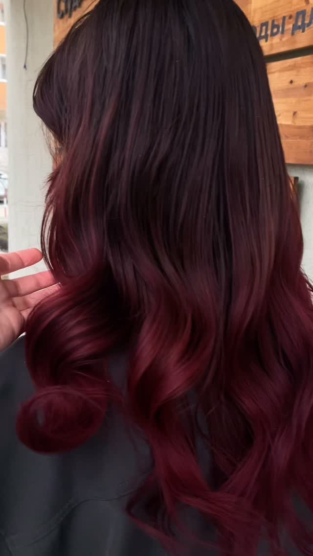 Long wavy hair with a dark maroon to bright burgundy ombre gradient.