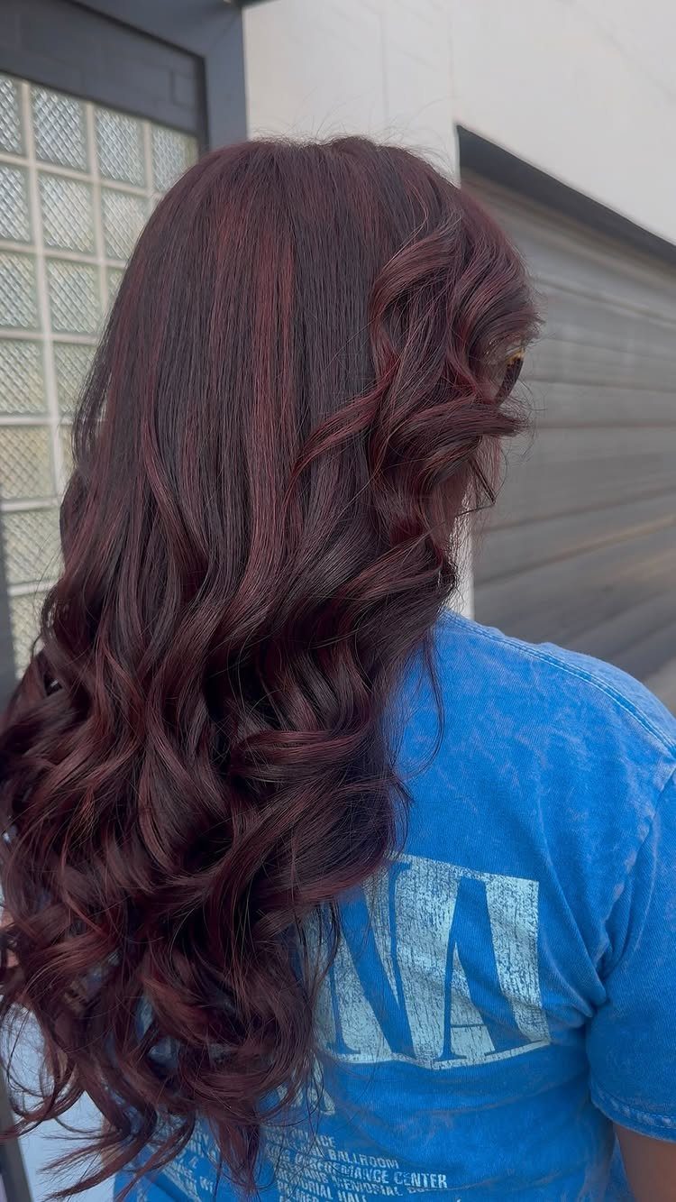 Long wavy hair dyed in a chocolate burgundy blend of brown and red.
